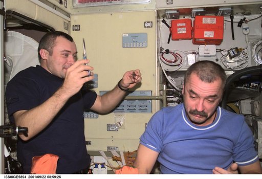 Dezhurov gives Tyurin a haircut in the Service Module during Expedition Three