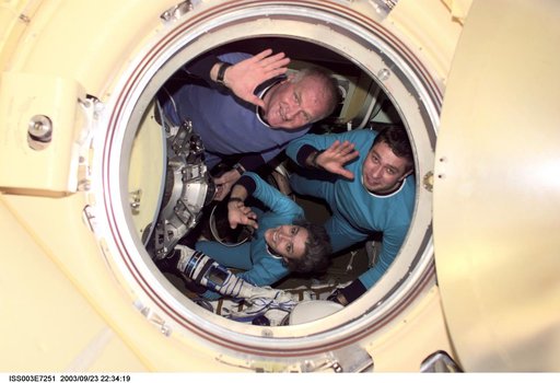 The Soyuz Taxi crew wave through a Soyuz hatch during their visit to the ISS