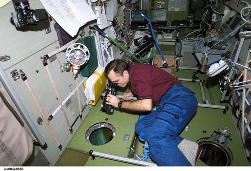 Walz uses binoculars to look out SM window during Expedition Four