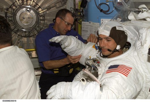 Expedition Six Flight Engineer Pettit is assisting STS-113 MS Herrington with his EMU Spacesuit
