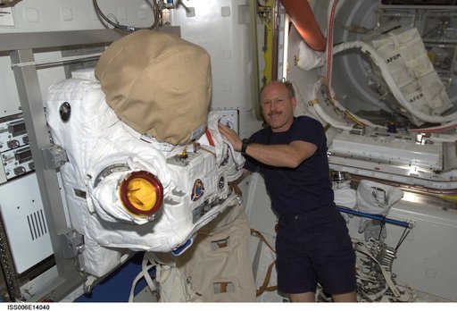 Commander Kenneth D. Bowersox poses next to the torso portion of an EVA in the Quest Airlock