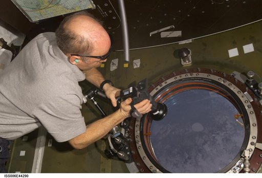 Commander Kenneth D. Bowersox uses a camera to photography the earth from the nadir window