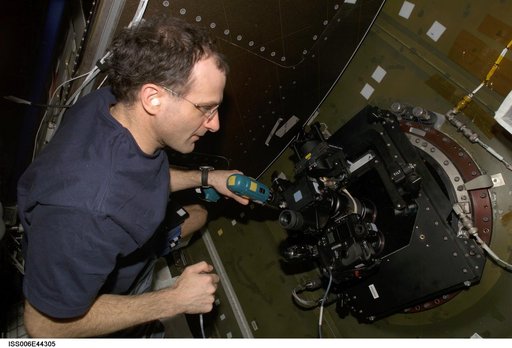 Pettit runs a drill while looking through  a camera mounted on the Nadir window in the U.S. Lab