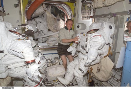 Fincke poses with stowed EMUs and EVA equipment in the Quest A/L during EXP 8 / EXP 9