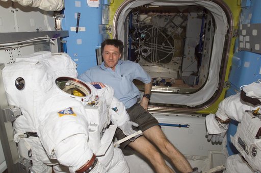 Foale poses with a stowed EMU and EVA equipment in the Quest A/L during EXP 8