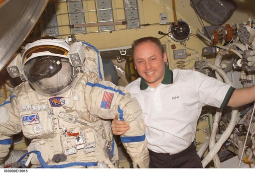 Fincke posses with an Orlan EVA suit inside the Pirs DC during Expedition 9