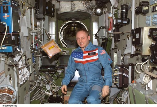 Fincke stands beside a floating bag of tomato seeds for the EPO Tomatosphere II project during Expedition 9