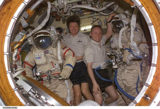 Padlaka and Fincke pose with Orlan suits inside the Pirs DC during Expedition 9