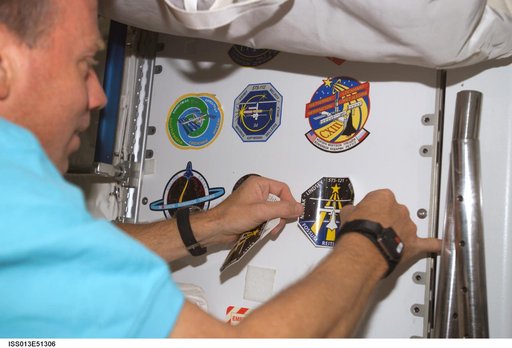 Lindsey place an STS-121 mission insignia patch on locker in the U S Lab during Expedition 13 / STS-121 joint operations