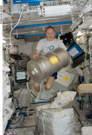 Expedition 21 Commander De Winne poses for a photo with a MSL FLSS