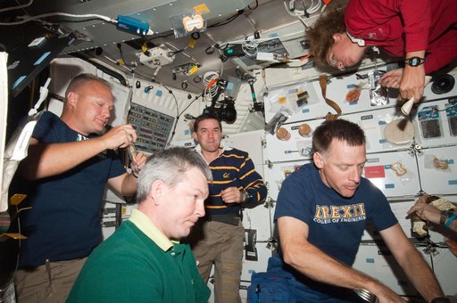 STS-135/Expedition 28 Crew Members during dinner on the Shuttle Middeck