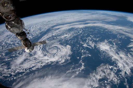 The space station orbits above a partly cloudy Pacific Ocean