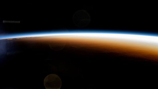 An orbital sunrise colorfully illuminates the Earth's atmosphere