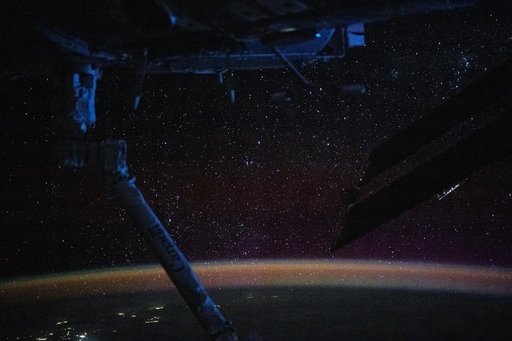 The atmospheric glow blankets Earth beneath a sparkling field of stars