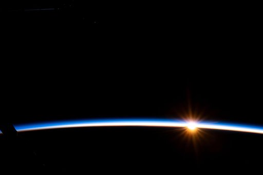 The first rays of an orbital sunrise illuminate Earth's atmosphere
