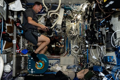 Astronaut Nick Hague pedals on an exercise cycle