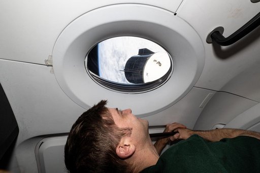 Astronaut Matthew Dominick looks out a window on the SpaceX Dragon Endeavour spacecraft