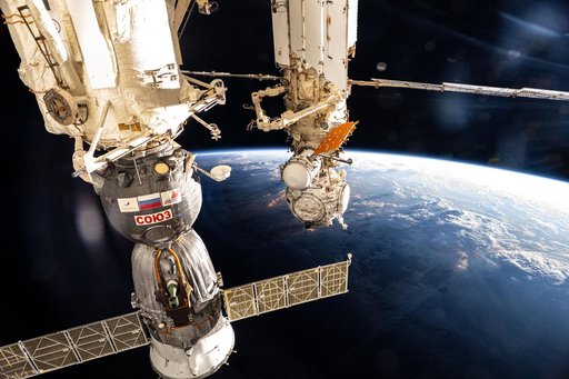 The International Space Station soars into an orbital sunset above a cloudy Pacific Ocean