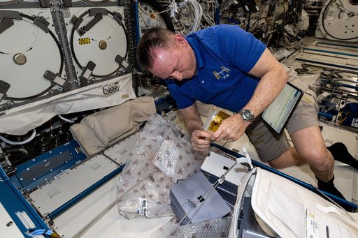 Astronaut Butch Wilmore swaps sample cassettes inside the Advanced Space Experiment Processor-4