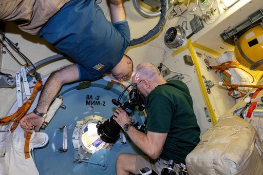 Astronaut Don Pettit points a camera outside a window for a sun photography session