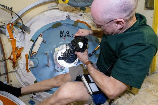 Astronaut Don Pettit points a camera outside a window for a sun photography session