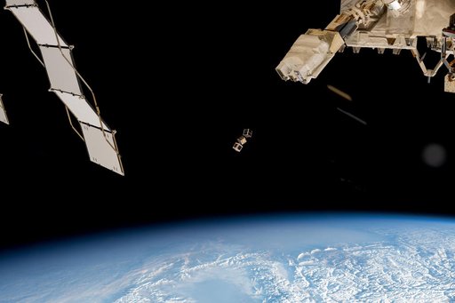 A trio of CubeSats is ejected into Earth orbit from a small satellite orbital deployer