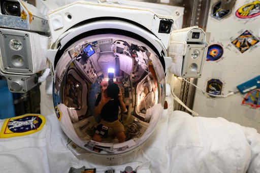 Astronaut Don Pettit's reflection is prominent on a spacesuit helmet's visor