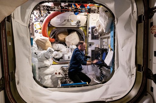 Astronaut Nick Hague works on a laptop computer inside the Quest airlock