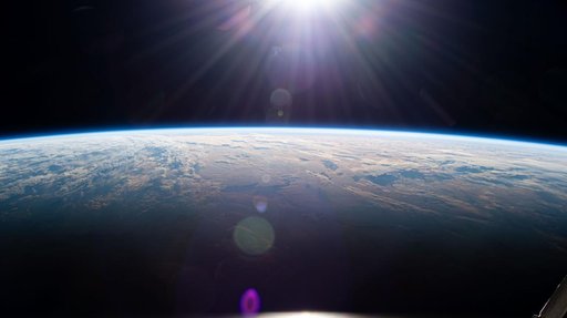 Sunrise above Earth's horizon begins illuminating a cloudy Indian Ocean