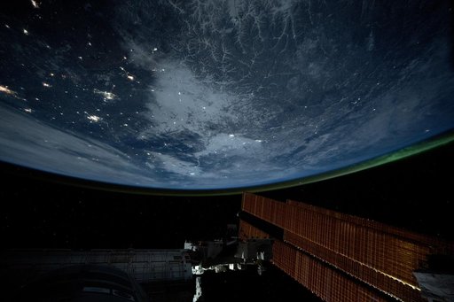 City lights dot the northeastern landscape of China with a wispy aurora above Earth's horizon