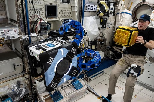 Astronaut Don Pettit watches an Astrobee robotic free-flyer grapple a "capture cube"