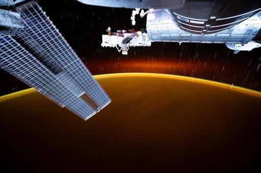Star trails and an atmospheric glow blanket Earth's horizon