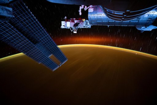 Star trails and an atmospheric glow blanket Earth's horizon