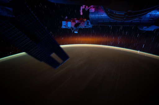Star trails and an atmospheric glow blanket Earth's horizon