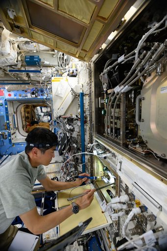 Astronaut Takuya Onishi inspects science hardware inside the Kibo laboratory module