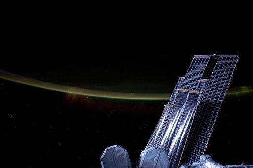 Moonlight casts a silvery light on a set of the space station's main solar arrays and rollout solar arrays
