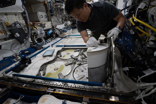 NASA astronaut Jonny Kim removes a cryogenic storage unit containing frozen protein crystal samples