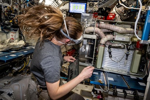 NASA astronaut Nichole Ayers works on an experimental carbon dioxide removal device