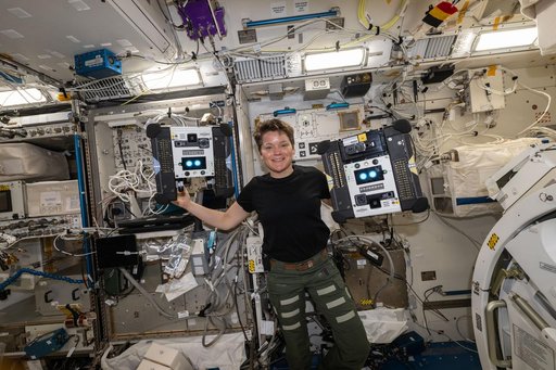 Astronaut Anne McClain shows off a pair of Astrobee robotic free-flyers