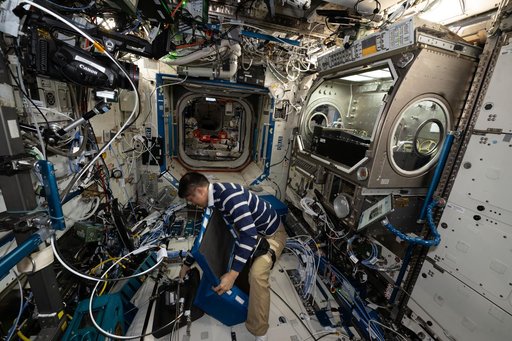 JAXA astronaut Takuya Onishi stows physics research hardware used during the Colloidal Solids experiment