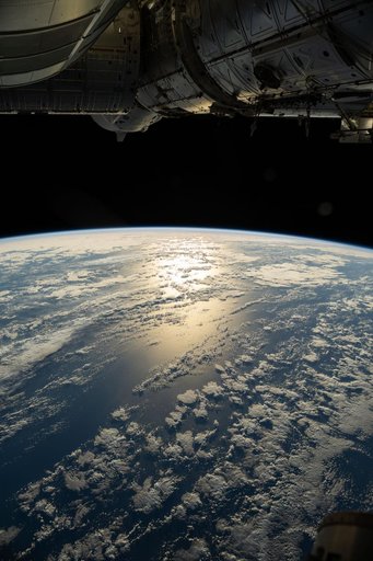 The sun's glint beams off a partly cloudy southern Pacific Ocean