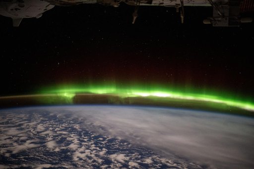 A bright green aurora australis streams above Earth's horizon