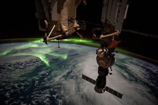 The aurora australis arcs back and forth above a partly cloudy Indian Ocean
