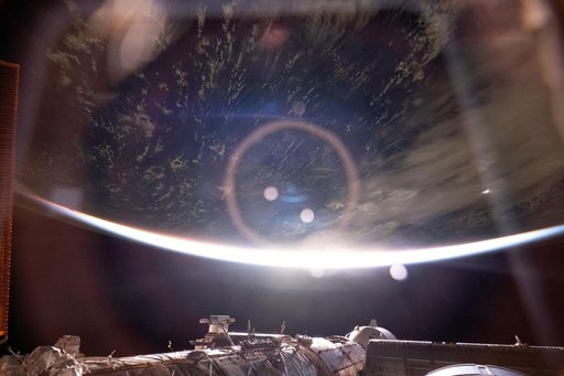 The light from an orbital sunrise refracts through a window inside the International Space Station