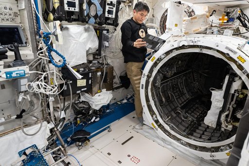JAXA astronaut Takuya Onishi prepares to retract a slide table that contains research hardware