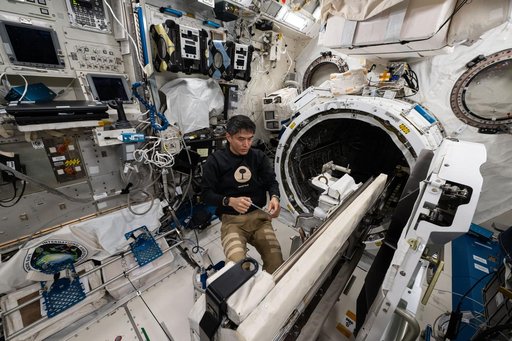 JAXA astronaut Takuya Onishi removes research hardware attached to the airlock slide table