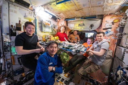 Expedition 73 crew members pose for a portrait during dinnertime