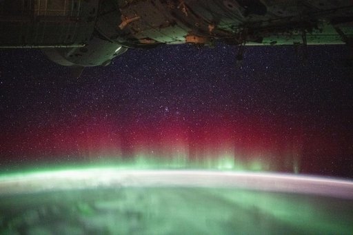 A vivid red and green aurora crowns Earth’s horizon