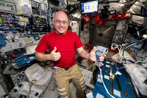 NASA astronaut gives a “thumbs up” while holding a spacesuit camera