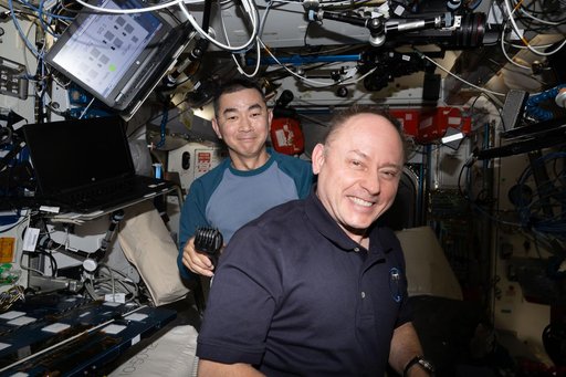 Astronauts Kimiya Yui and Mike Fincke smile for a portrait during a haircut
